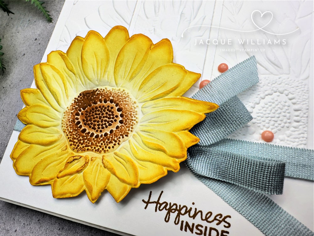 Clean and simple handmade card featuring the Stampin’ Up! Sunflower Embossing Folder, with a bold yellow die-cut sunflower, subtle embossed white background, and soft blue ribbon—perfect for cardmaking inspiration, embossing folder techniques, and papercraft project ideas.